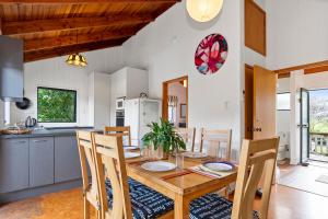 una cucina e una sala da pranzo con tavolo e sedie in legno di Riverview Retreat - Cooks Beach Holiday Home a Cooks Beach Altre 9 foto