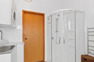 a bathroom with a shower and a wooden door at Riverview Retreat - Cooks Beach Holiday Home in Cooks Beach