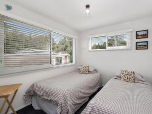 KuratauにあるGreat Lake Oasis - Kuratau Holiday Homeの窓のある小さな部屋にベッドが2つある
