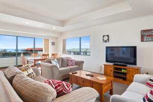 a living room with couches and a flat screen tv at White Island Views - Ohope Holiday Home in Ohope Beach