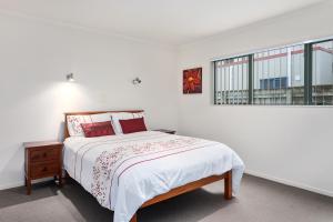 a white bedroom with a bed and a window at White Island Views - Ohope Holiday Home in Ohope Beach