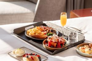 Crowne Plaza Hobart, an IHG Hotel في هوبارت: صينية طعام الإفطار على طاولة مع كوب من عصير البرتقال