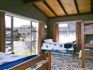 a bedroom with two beds and a large window at Golders Heights - Taupo Holiday Home in Taupo