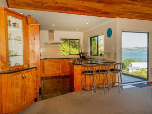 eine Küche mit einer Insel mit Barhockern in der Unterkunft View from the Top - Whitianga Holiday Home in Whitianga