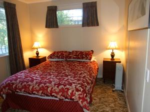 1 dormitorio con 1 cama roja y 2 lámparas en Kuratau - Kuratau Bach, en Kuratau