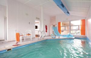a pool with a slide and chairs in a room at Dnenpark 15 - Dorf 6 in Travemünde