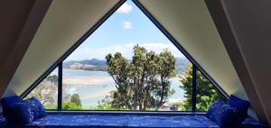 a room with a large window looking out at a lake at Paku Escape - Tairua Bach in Tairua +6 photos