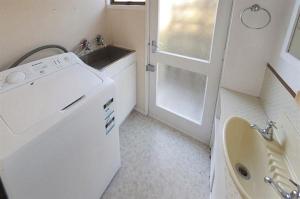 a small bathroom with a sink and a washing machine at Joes Place - Cooks Beach Holiday Home in Cooks Beach +18 photos