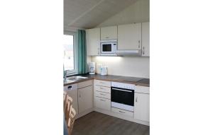 a small kitchen with white cabinets and appliances at Freibeuterweg 9 - Dorf 5 in Travemünde +15 photos