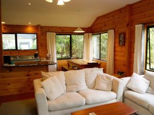 uma sala de estar com um sofá branco e janelas em Puka Lodge Front dwelling - Pukawa Bay Home em Kuratau