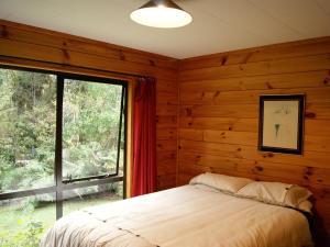 um quarto com uma cama e uma grande janela em Puka Lodge Front dwelling - Pukawa Bay Home em Kuratau
