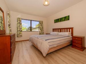 1 dormitorio con 1 cama, vestidor y ventana en The Bach Retreat - Hahei Holiday House, en Hahei