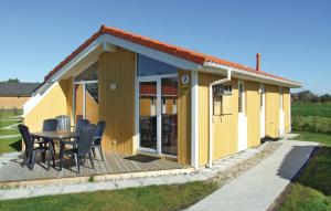 a yellow house with a table and chairs on a deck at Friedrichskoog-Deichblick 7 in Friedrichskoog