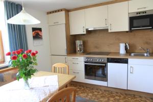 a kitchen with white cabinets and a table with red roses at Haus Tschofen in Schruns