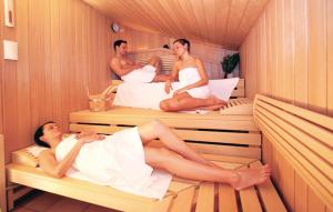 3 Männer und eine Frau in einer Sauna in der Unterkunft Friedrichskoog-strandpark 10 in Friedrichskoog