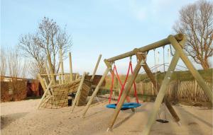 einen Spielplatz mit zwei Schaukeln im Sand in der Unterkunft Ferienhaus Seeigel K in Süssau