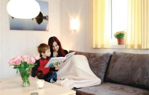 a woman and child sitting on a couch reading a book at Friedrichskoog-Deichblick 3 in Friedrichskoog