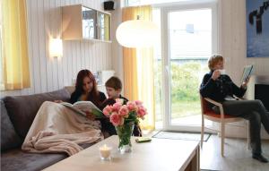 two women and a child sitting on a couch reading a book at Friedrichskoog-Deichblick 3 in Friedrichskoog