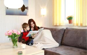 a woman and a boy sitting on a couch reading a book at Friedrichskoog-Deichblick 5 in Friedrichskoog