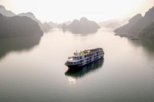 a boat on a river with mountains in the background at Mon Cheri Cruises in Ha Long