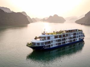 a cruise ship on a river with mountains in the background at Mon Cheri Cruises in Ha Long
