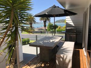 a patio with a table and an umbrella at Beach Pod Studio - Tairua Bach in Tairua +5 photos