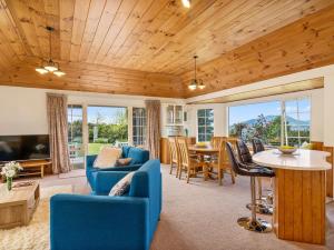 a living room with a blue couch and a table at Laketop Retreat - Acacia Bay Holiday Home in Taupo