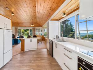 a kitchen with white cabinets and a large window at Laketop Retreat - Acacia Bay Holiday Home in Taupo +11 photos