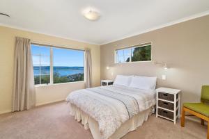 a bedroom with a bed and a large window at Laketop Retreat - Acacia Bay Holiday Home in Taupo