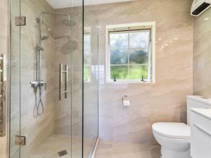 a bathroom with a shower with a toilet and a window at Laketop Retreat - Acacia Bay Holiday Home in Taupo