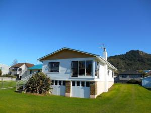 a white house with a hill in the background at Bobs Bach - Mt Maunganui Bach in Mount Maunganui