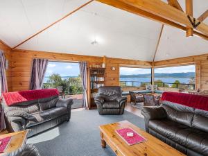 sala de estar con muebles de cuero y ventanas grandes. en Lakewood - Omori Holiday Home en Kuratau