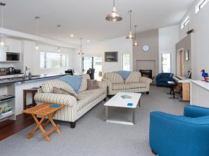 a living room with two couches and a kitchen at Poolside Retreat - Picton Holiday House Waikawa in Picton