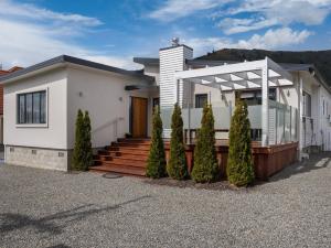 una casa blanca con porche y algunos árboles en Poolside Retreat - Picton Holiday House Waikawa, en Picton