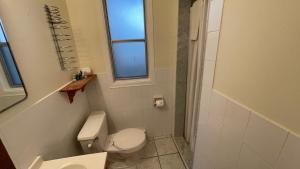 a small bathroom with a toilet and a window at Beach Club by Beach1 Motel in Wasaga Beach +23 photos