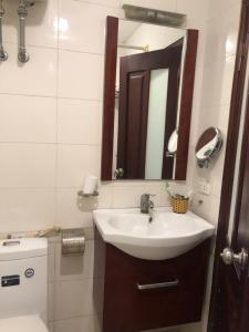 a bathroom with a sink and a mirror and a toilet at Hanoi Charming House in Hanoi