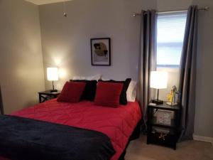 a bedroom with a bed with red sheets and two lamps at *NEW*ENTIRE HOME IN ROSE DISTRICT*DINE*SHOP*FUN in Broken Arrow