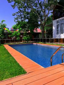 a swimming pool with a wooden walkway next to a house at Qafqaz Fountain Villa in Gabala