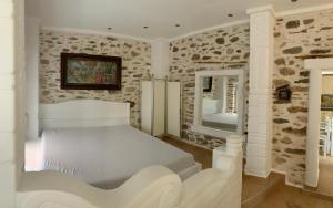 a bedroom with a white bed and a stone wall at Sea&Stone Apartment in Skala Sotiros
