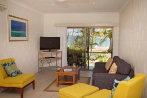Una sala de estar con un sofá y un televisor. en Apollo Jewel Beachfront Apartments, en South Mission Beach