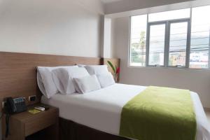 a bedroom with a bed with a telephone and a window at Hotel Monte Cafeto INN in Pichanaki