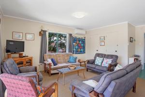 a living room with couches and chairs and a tv at Room for The Family - Bowentown Bach in Waihi Beach