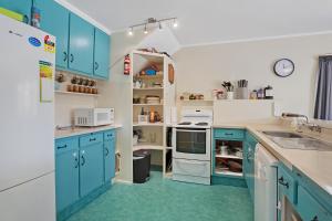 a kitchen with blue cabinets and green floors at Room for The Family - Bowentown Bach in Waihi Beach