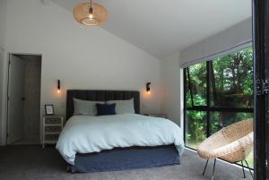 a bedroom with a large bed and a large window at Lake View Okareka - Lake Okareka Holiday Home in Lake Tarawera