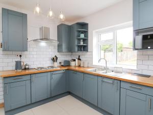 Una cocina con gabinetes azules y un fregadero. en Welsh Valley House, en Brynamman