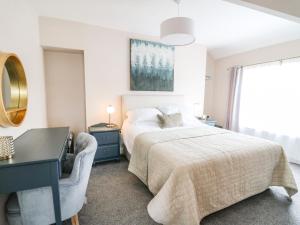 a white bedroom with a bed and a desk and a window at Welsh Valley House in Brynamman