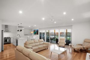 a living room with a couch and chairs and a kitchen at 108 Madaffari Drive in Exmouth