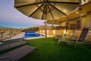 un patio con bancos y una sombrilla junto a la piscina en 7 Kestrel Place, en Exmouth