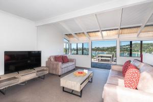 a living room with couches and a flat screen tv at The Tide Watcher - Okiato Holiday Home in Opua