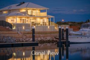 a large house with a boat in the water at 32 Corella Court in Exmouth